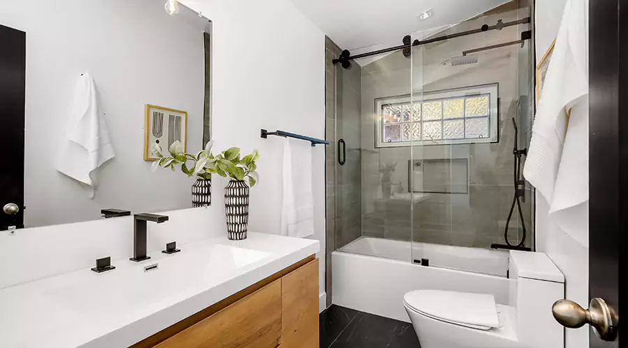 Modern bathroom featuring dark green vertical subway tile, charcoal vanity with gold hardware, and brass faucets.